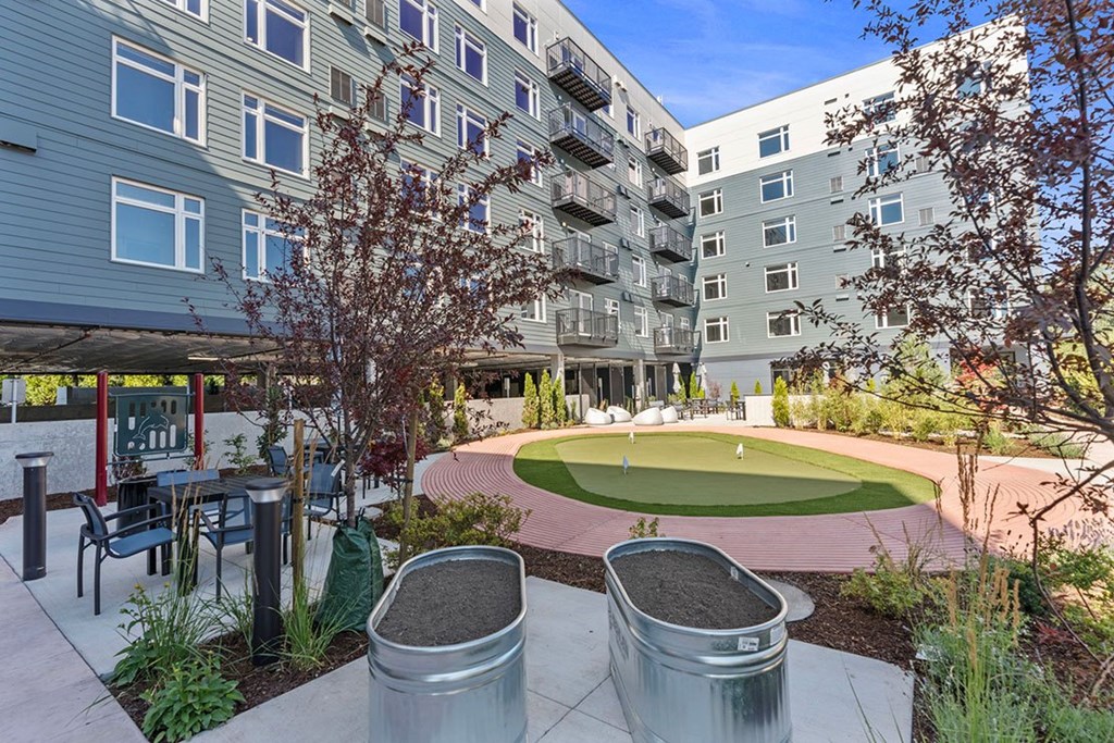 A patio area with a table and chairs is surrounded by apartment buildings