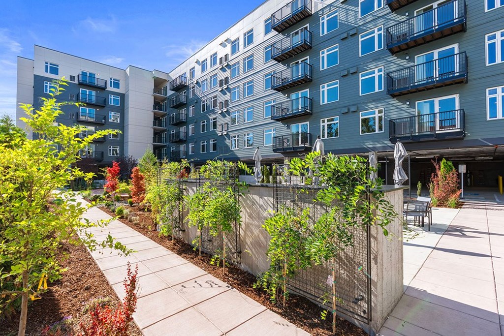A modern apartment complex with a well-maintained garden in front