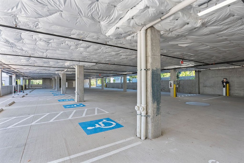 A parking garage with a few parking spaces and a few pillars.