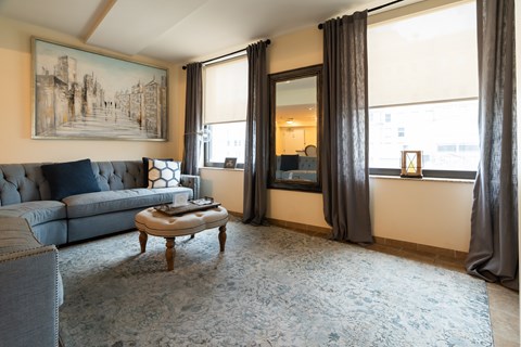 A living room with a blue couch and a large painting on the wall.