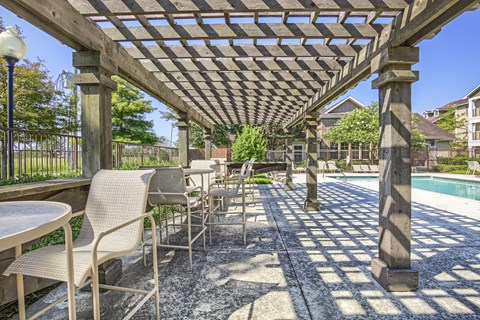 A patio with a table and chairs under a wooden pergola.