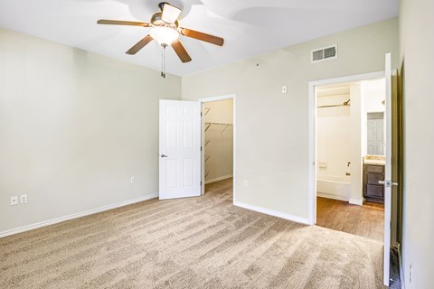 A room with a ceiling fan and carpeted floor.