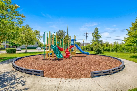 A playground with a red slide and green and yellow play structures.