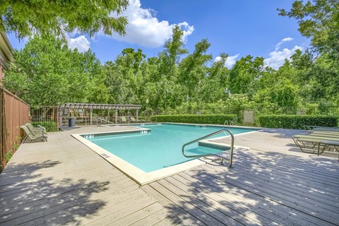 A wooden deck surrounds a rectangular pool.