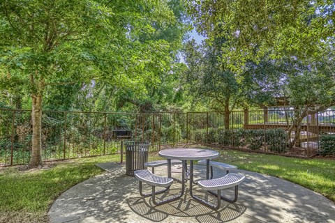A picnic table surrounded by four benches in a park.