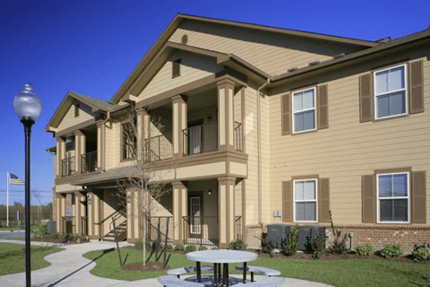 A large apartment building with a balcony and a flag on the left.