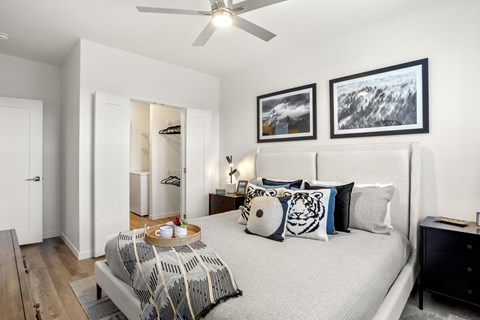 A bedroom with a bed, dresser, and a ceiling fan.