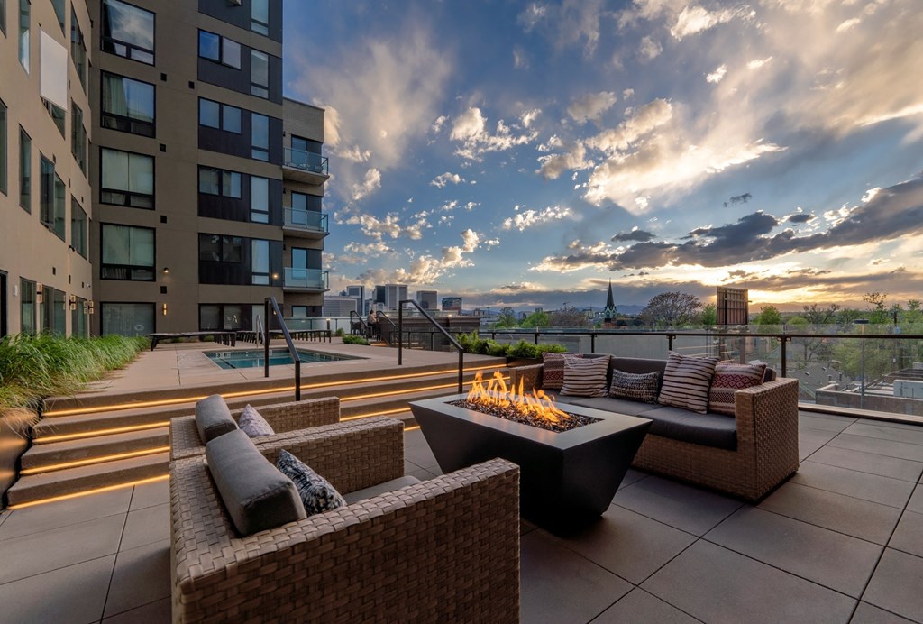an outdoor patio with couches and a fire pit on a rooftop