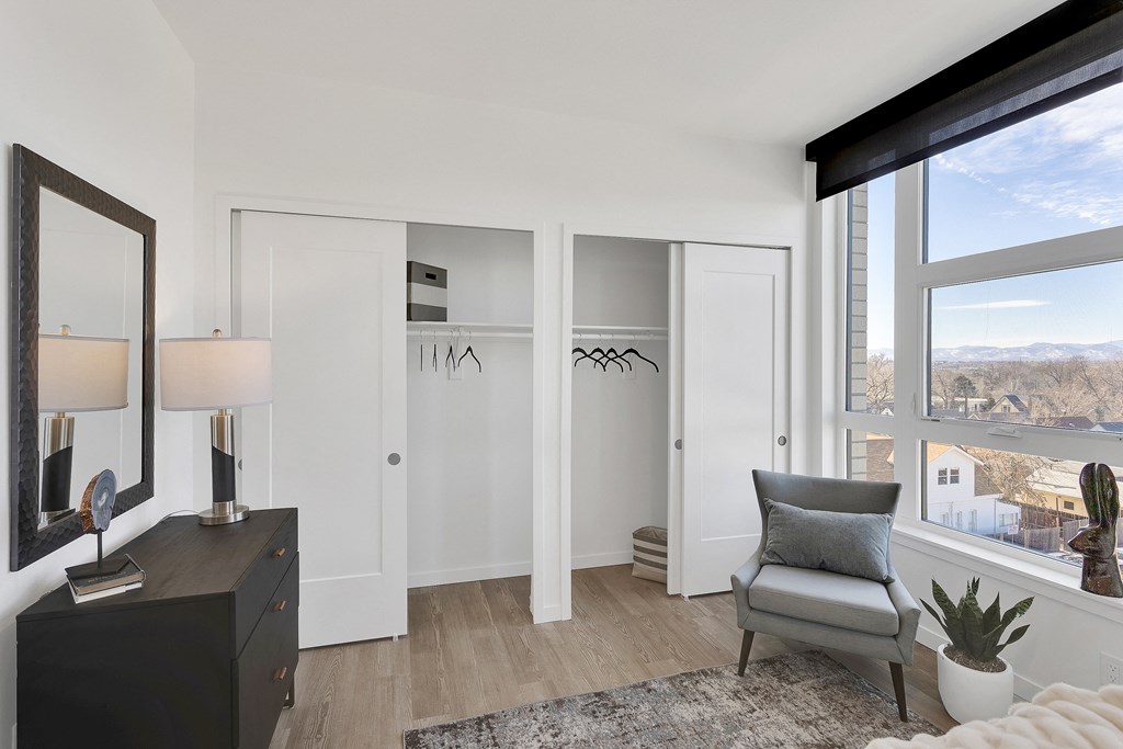 a bedroom with white walls and a large window with a view of a city