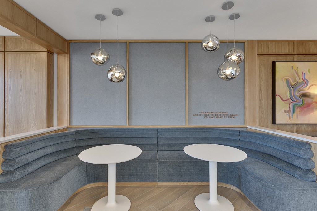 a seating area with a blue couch and two white tables