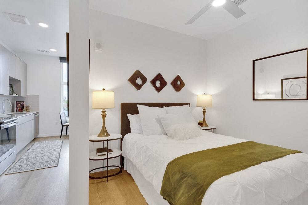 a bedroom with a bed and a kitchen in the background