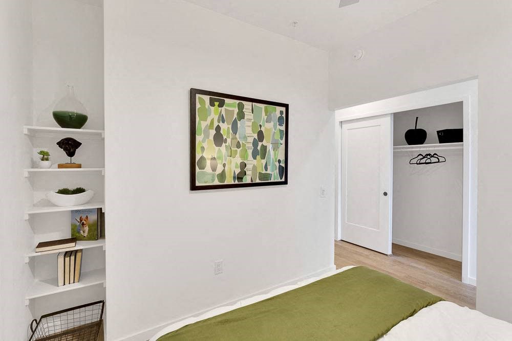 a bedroom with a green blanket and a painting on the wall