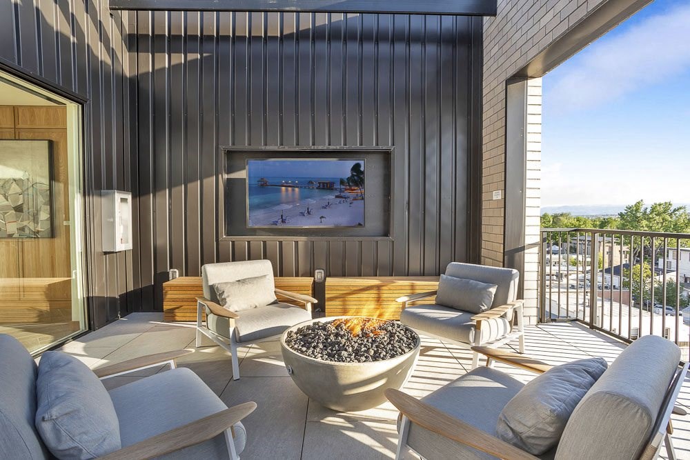 a patio with a fire pit and a tv on the wall
