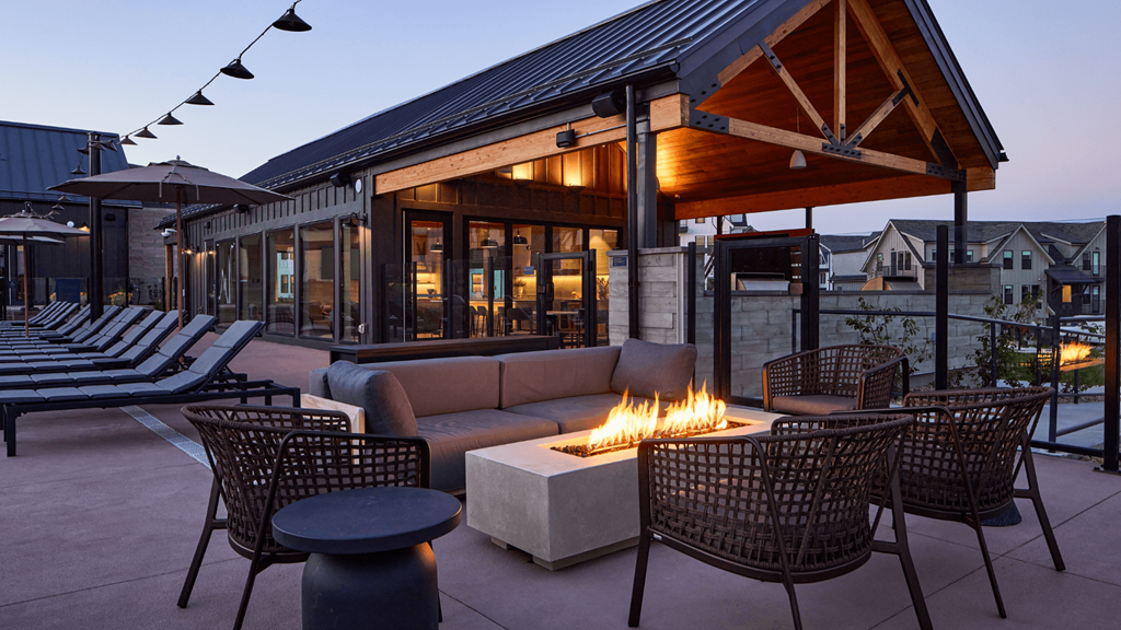a patio with a fire pit and chairs