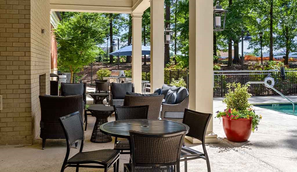 a patio with tables and chairs next to a swimming pool