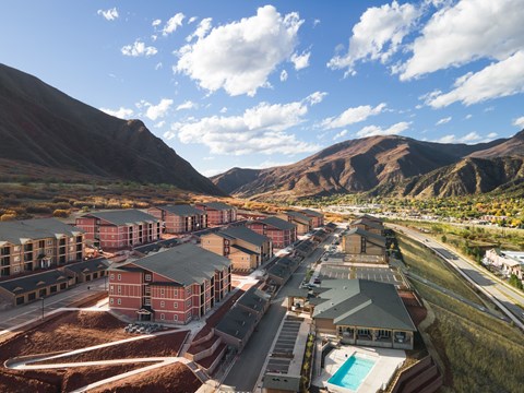 A large building complex with a swimming pool in the foreground and mountains in the background.