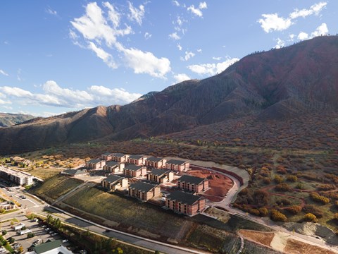 A large building complex sits in a valley with mountains in the background.