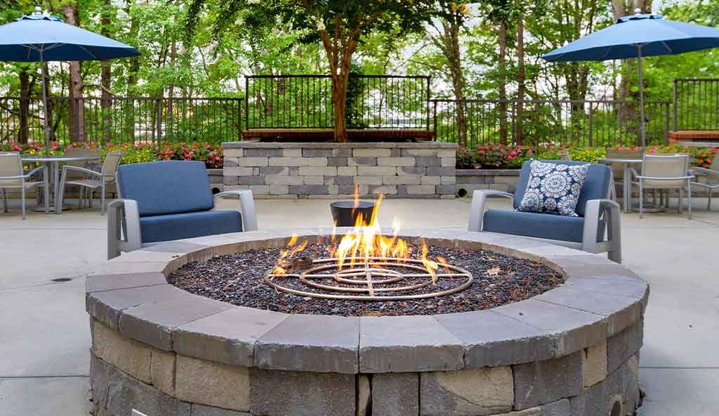 a fire pit with chairs and umbrellas on a patio