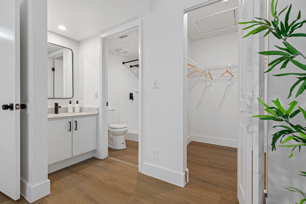 a bathroom with white walls and wood flooring