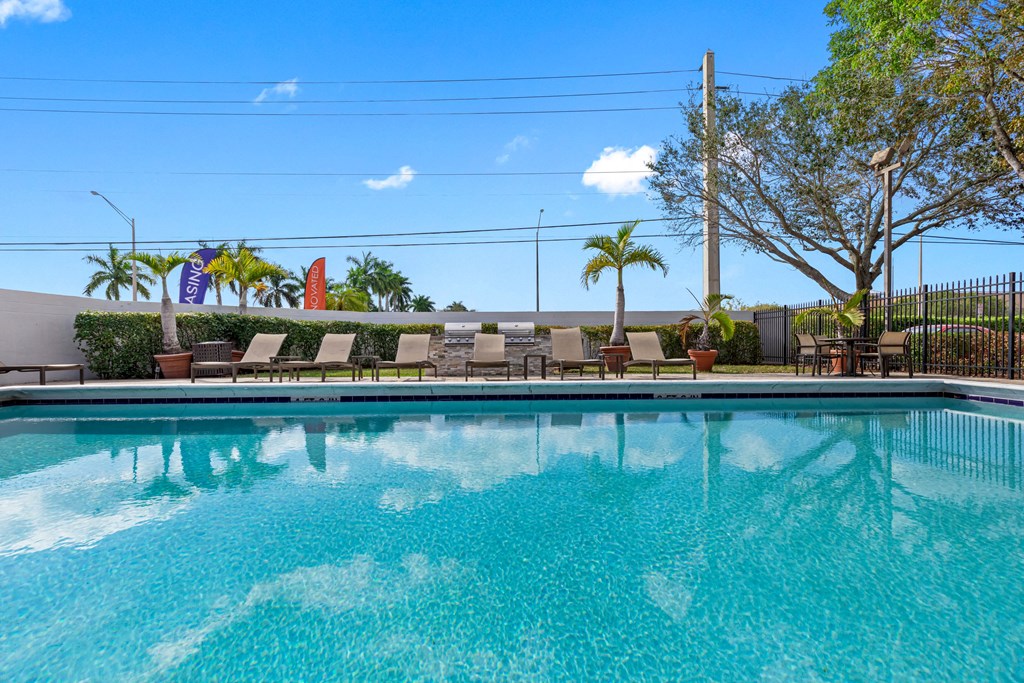 a large pool with lounge chairs and trees in the background