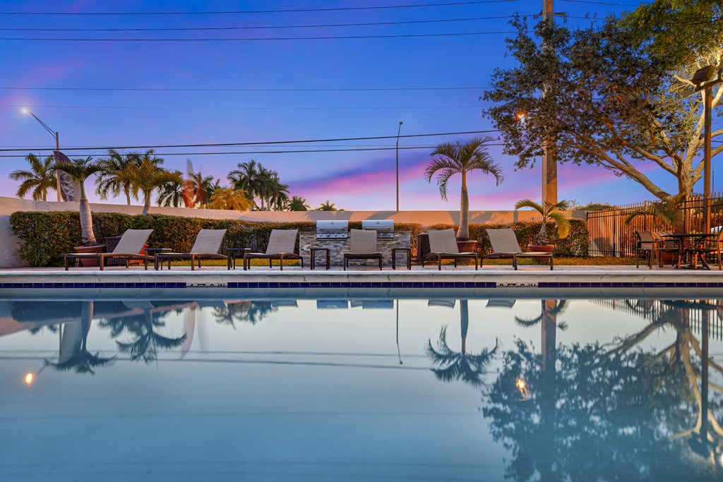a pool with lounge chairs and a grill