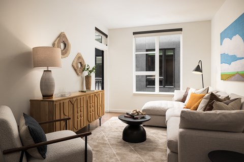 A living room with a grey couch, a wooden cabinet, and a painting on the wall.