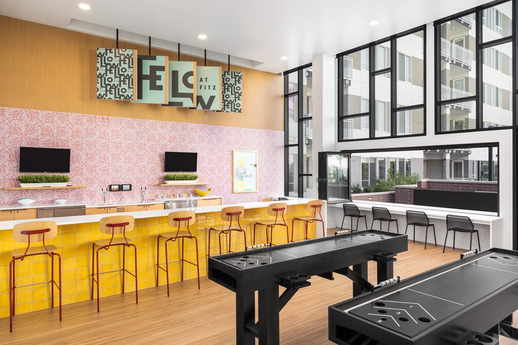 a common area with a pool table and a bar with stools
