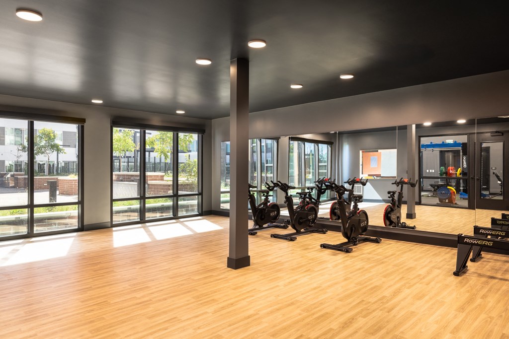 a gym with a wood floor and a row of exercise bikes
