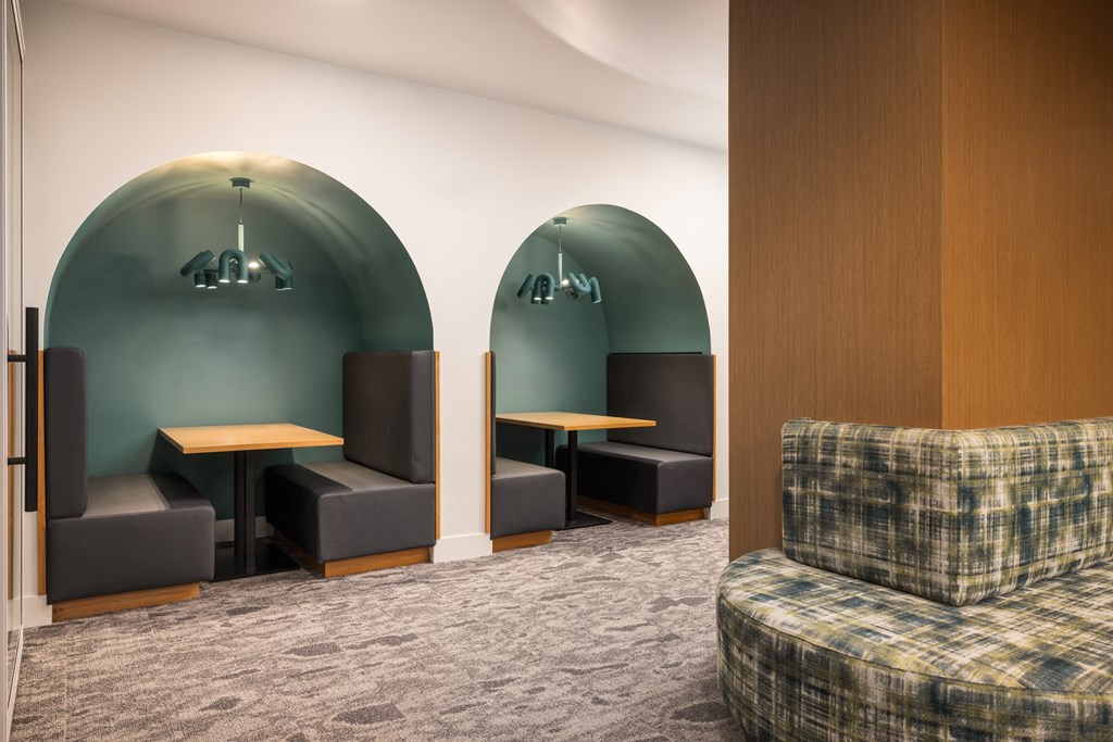 a lounge area with tables and chairs and a wall with a green accent wall