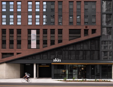 A building with a black awning and a bicycle rider in front.