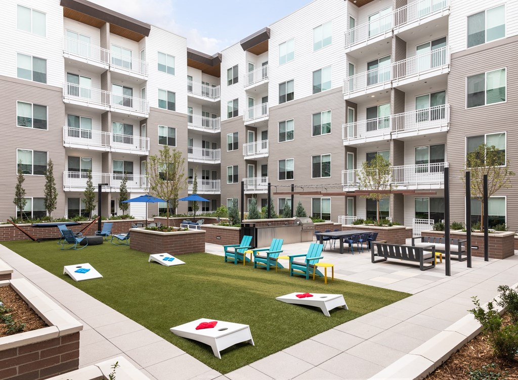 Apartment complex with a grassy courtyard and seating area.