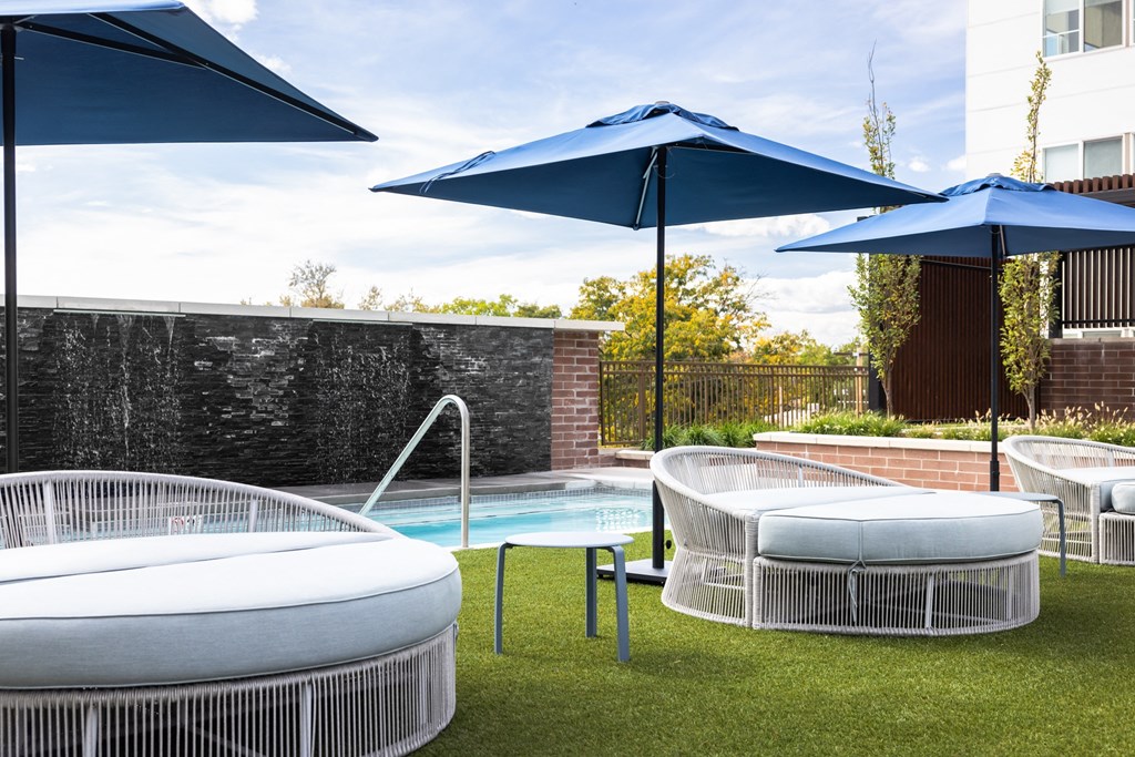 A pool with a white fence and a blue umbrella.