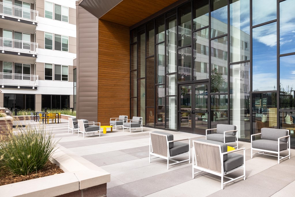 A modern outdoor seating area with white chairs and a wooden bench.