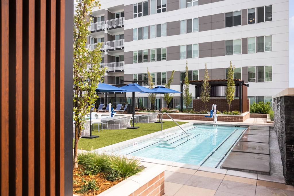 A pool area with a blue umbrella and a building in the background.