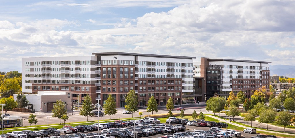 A large multi-story building with a parking lot in front.