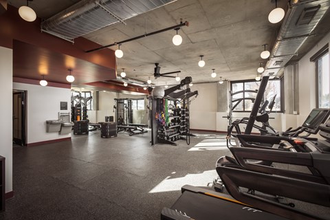 a gym with treadmills and other exercise equipment in a large room with windows
