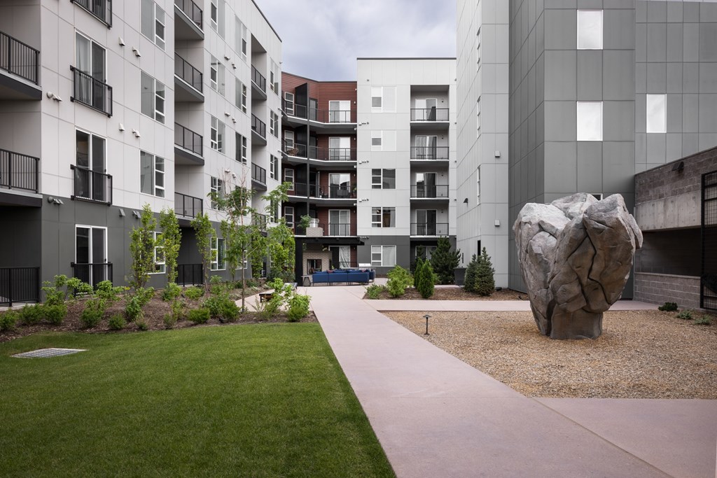 A modern apartment complex with a large rock sculpture in the courtyard.