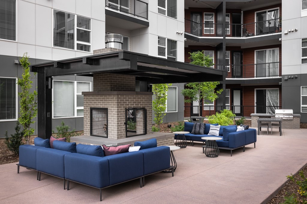 A patio with a blue couch and a fireplace.