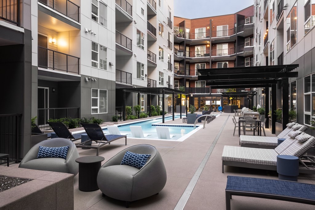 A large outdoor pool area with lounge chairs and a hot tub.