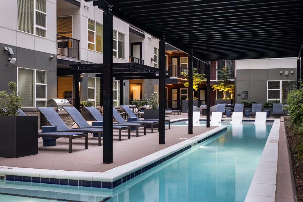 A pool with lounge chairs and a building in the background.