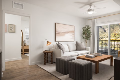 A living room with a white sofa, a wooden coffee table, and a painting on the wall.