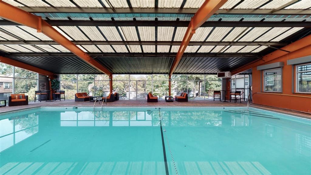 a swimming pool with chairs and a table in front of a window