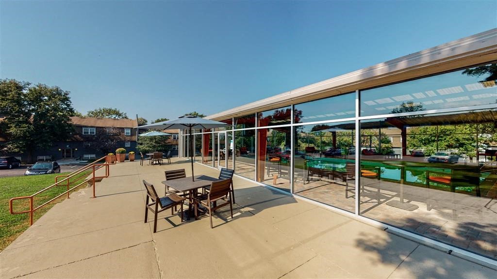 a patio with a table and chairs and a pool in the background