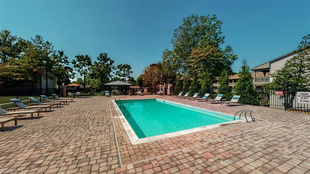 a swimming pool with chaise lounge chairs and trees in the background