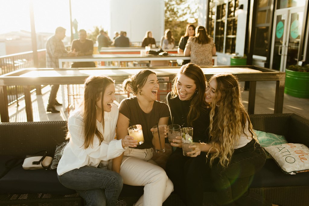 four women sitting on a couch holding drinks