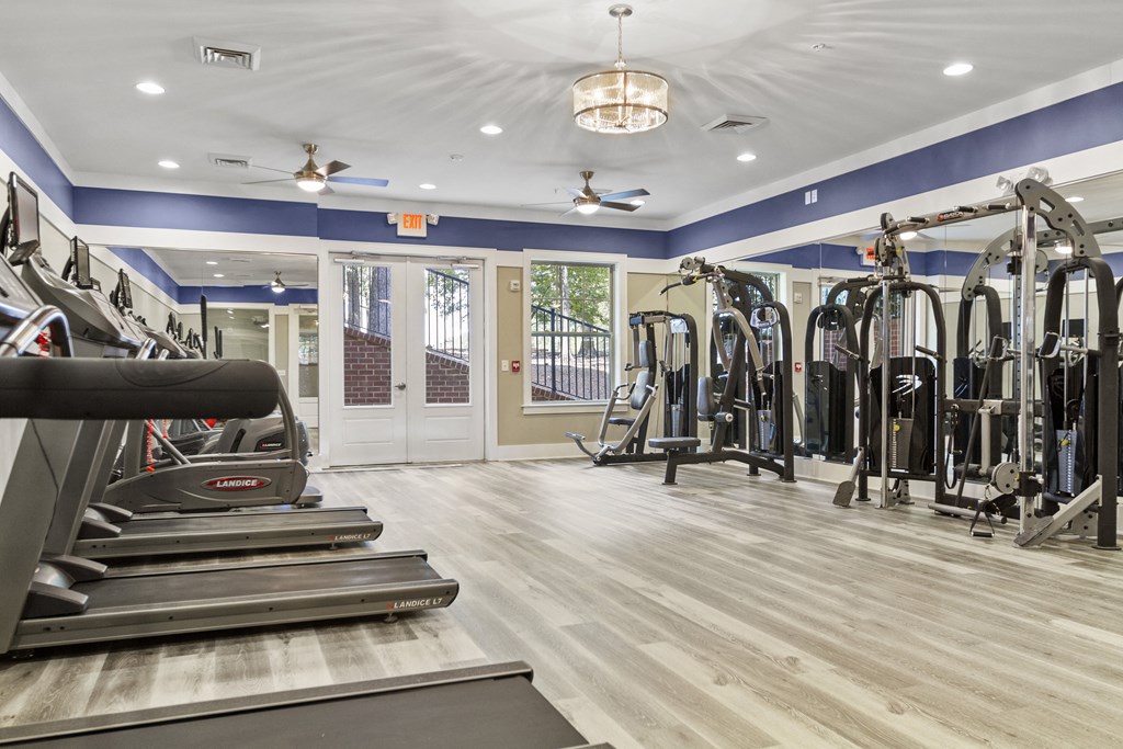 a gym with cardio machines and weights on the floor and a doorway