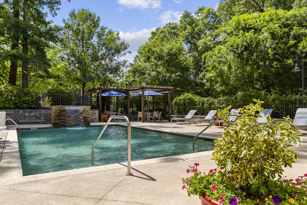 a swimming pool with chairs and trees in the background