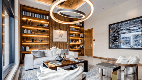A modern living room with a large bookshelf and a painting on the wall.