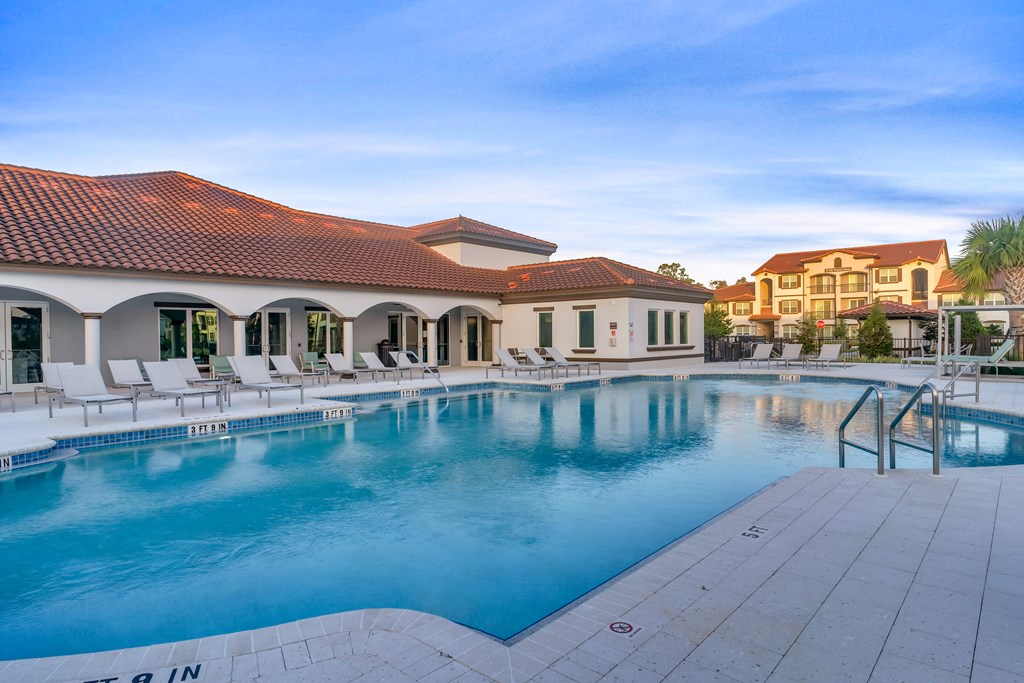 A large swimming pool with a red tiled roof and white lounge chairs.