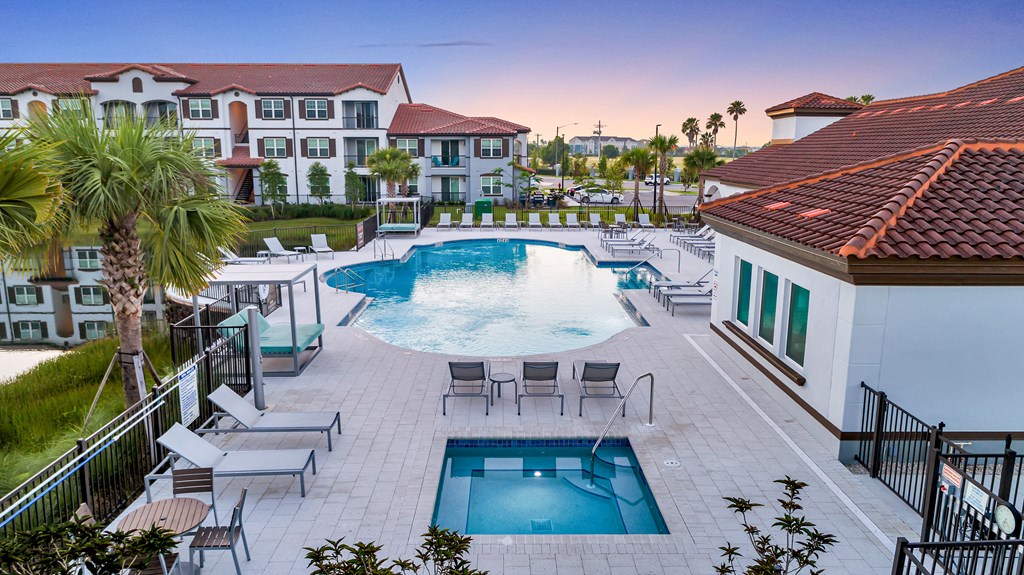 A pool area with a hot tub and lounge chairs.